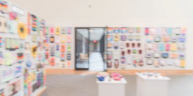 Galería de arte con paredes llenas de cuadros coloridos y mesas con objetos.