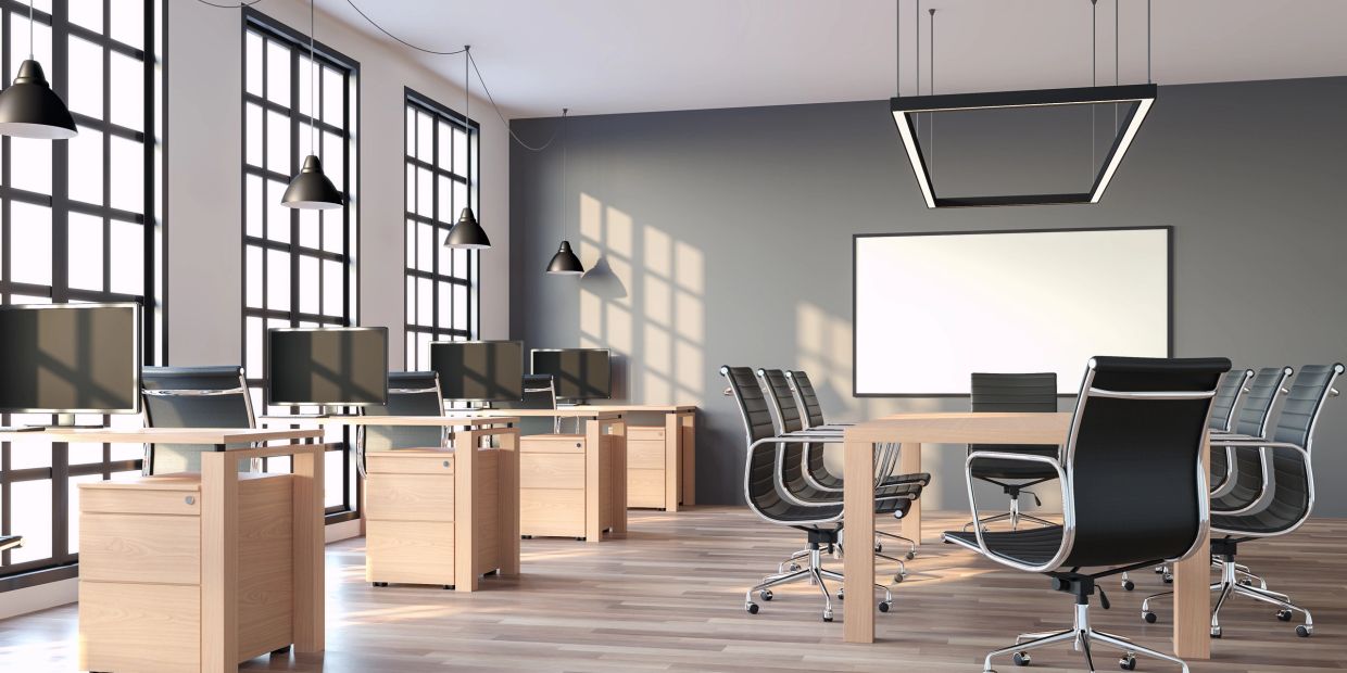 Modern office space with desks, chairs, and large windows.
