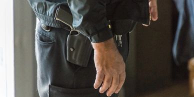Man with a gun tucked into his waistband.