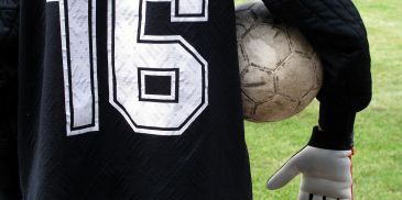 Soccer player holding a ball under arm.