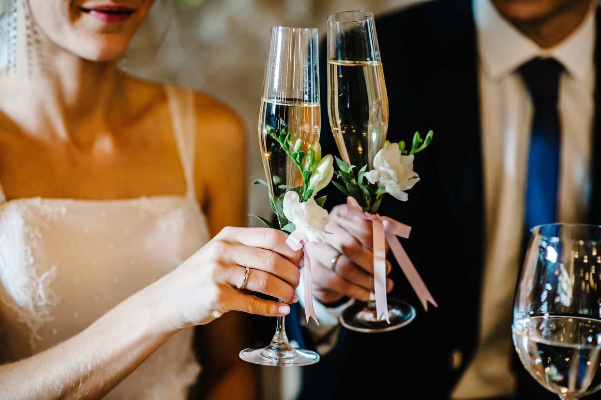 Couple toasting with decorated champagne glasses at wedding.