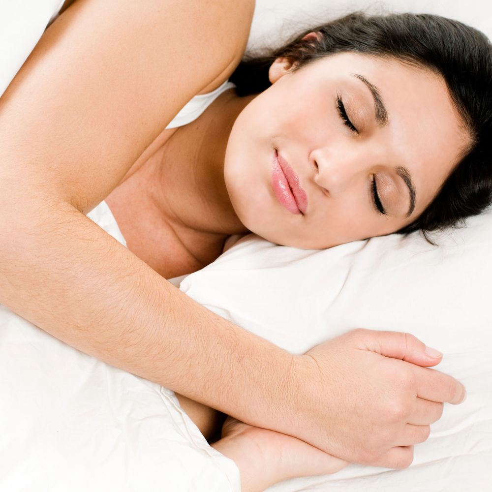 A woman peacefully sleeping on a white pillow.
