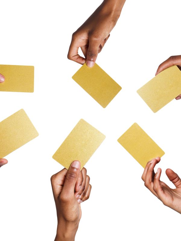 Hands holding blank gold cards on white background.