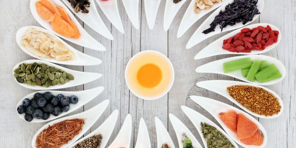 Various dried fruits, seeds, and herbs arranged around a cup of tea.