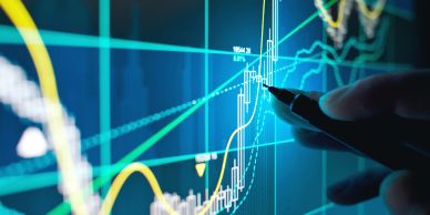 Person pointing at a stock market chart on a digital screen.