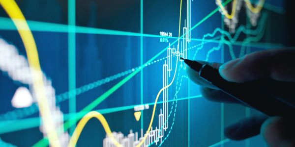 Hand pointing at rising stock market graph on screen.