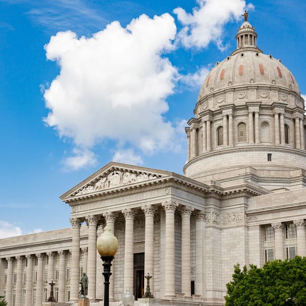 Classical government building with a large dome and columns under a blue sky.