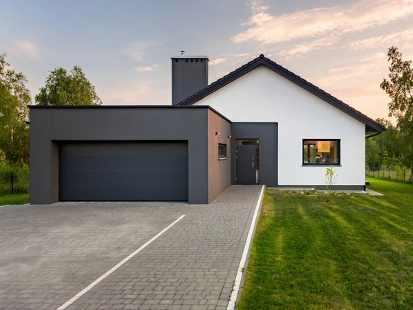 Modern house with dark gray garage and white facade at sunset.