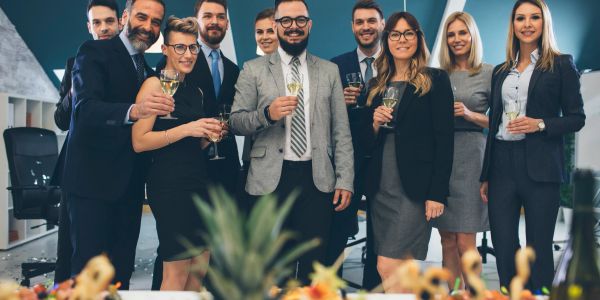 Group of professionals celebrating with drinks in an office.