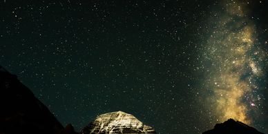 Snow-capped mountain under a starry night sky with the Milky Way.