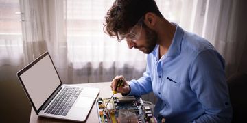 Man repairing computer hardware with tools at home.