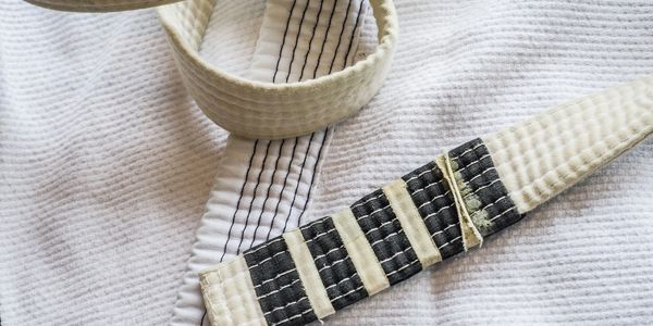 A BJJ Gi and white belt with four stripes