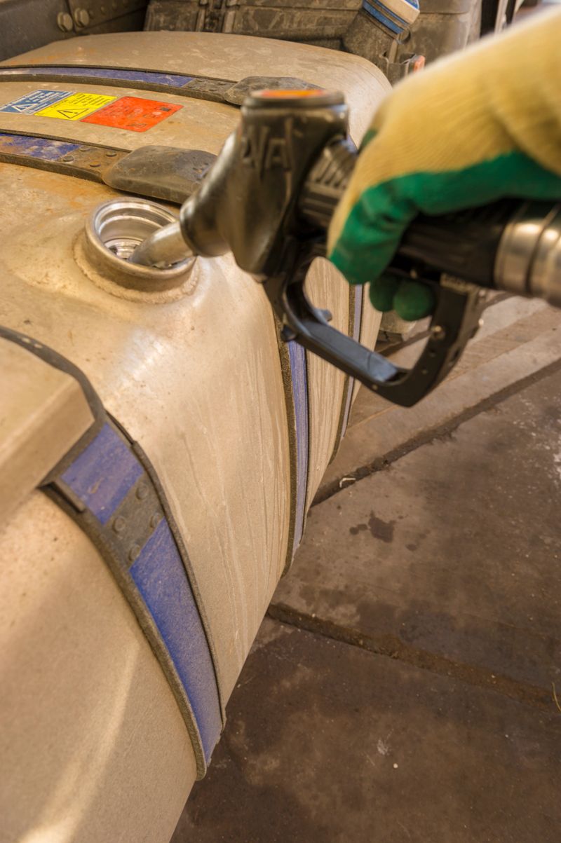 HGV Truck being refueled at the Service station with Gloved hand Showing in the image, Side View of Fuel tank leading from the lower Corner.
