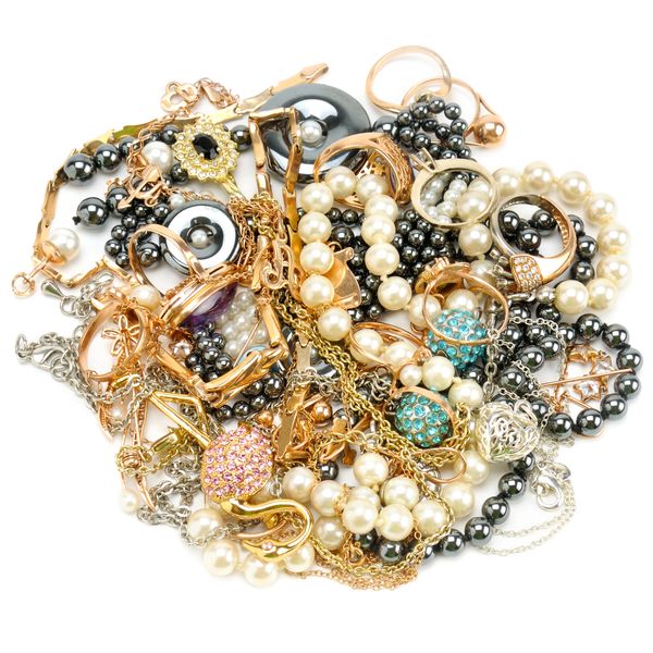 A tangled pile of assorted jewelry including pearls, rings, and chains in gold, silver, and black.