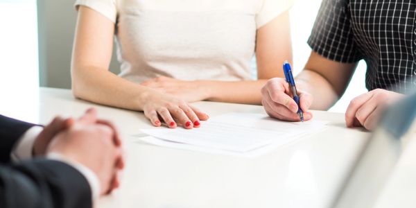 Two people signing a document in an office setting.