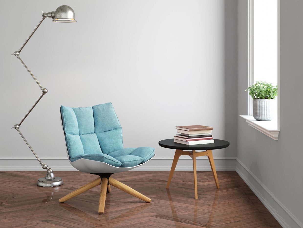 Minimalist reading nook with a blue cushioned chair and stack of books.