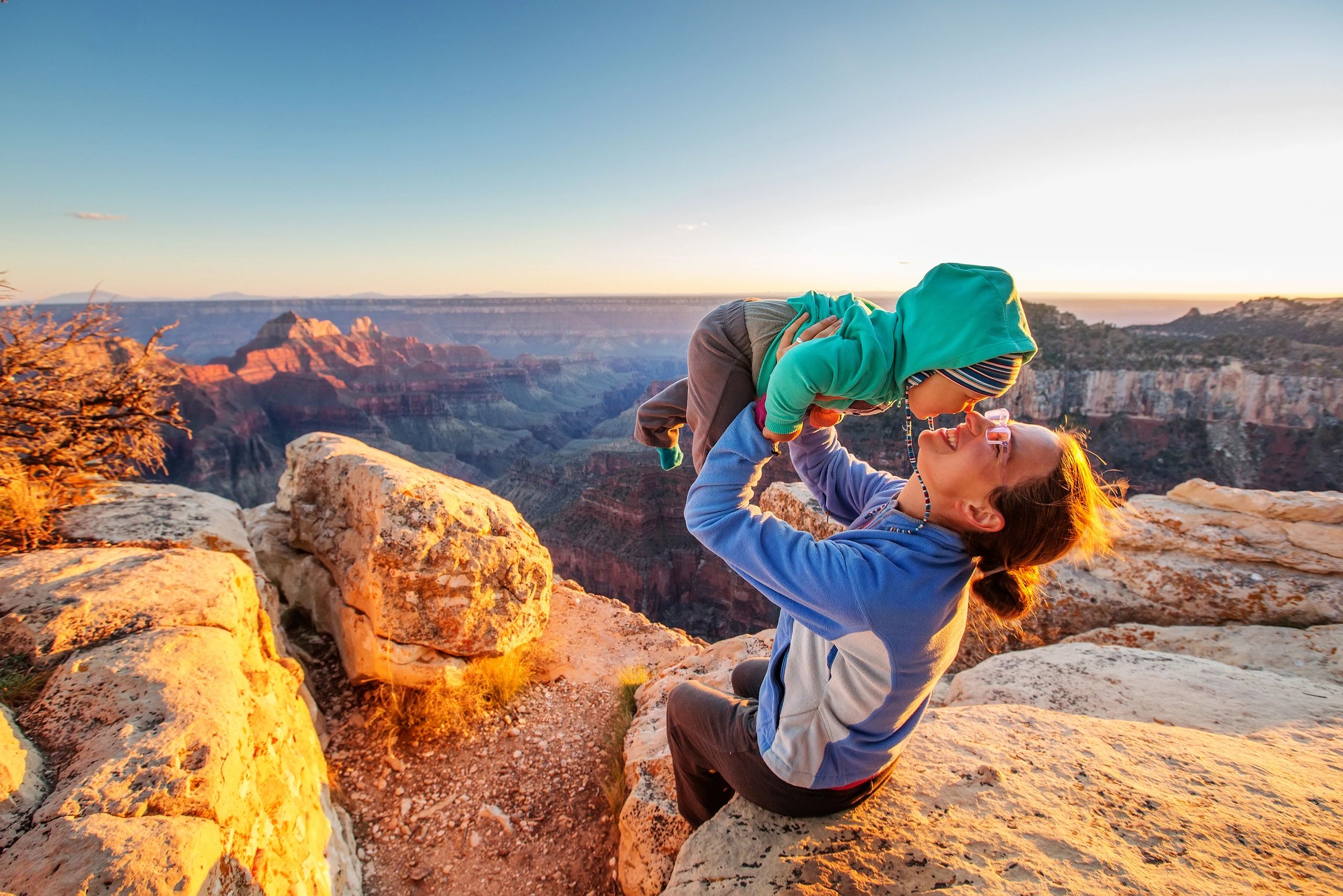 Mother laughing with her baby at sunset, framed by the warm glow of an Arizona canyon.