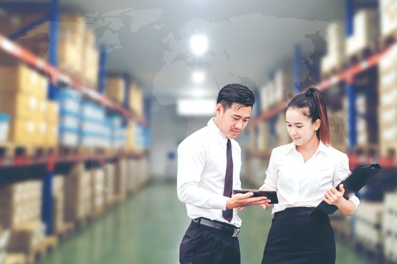 Asian Business man and Business woman worker in warehouse using tablet checking boxes Logistic import and export concept