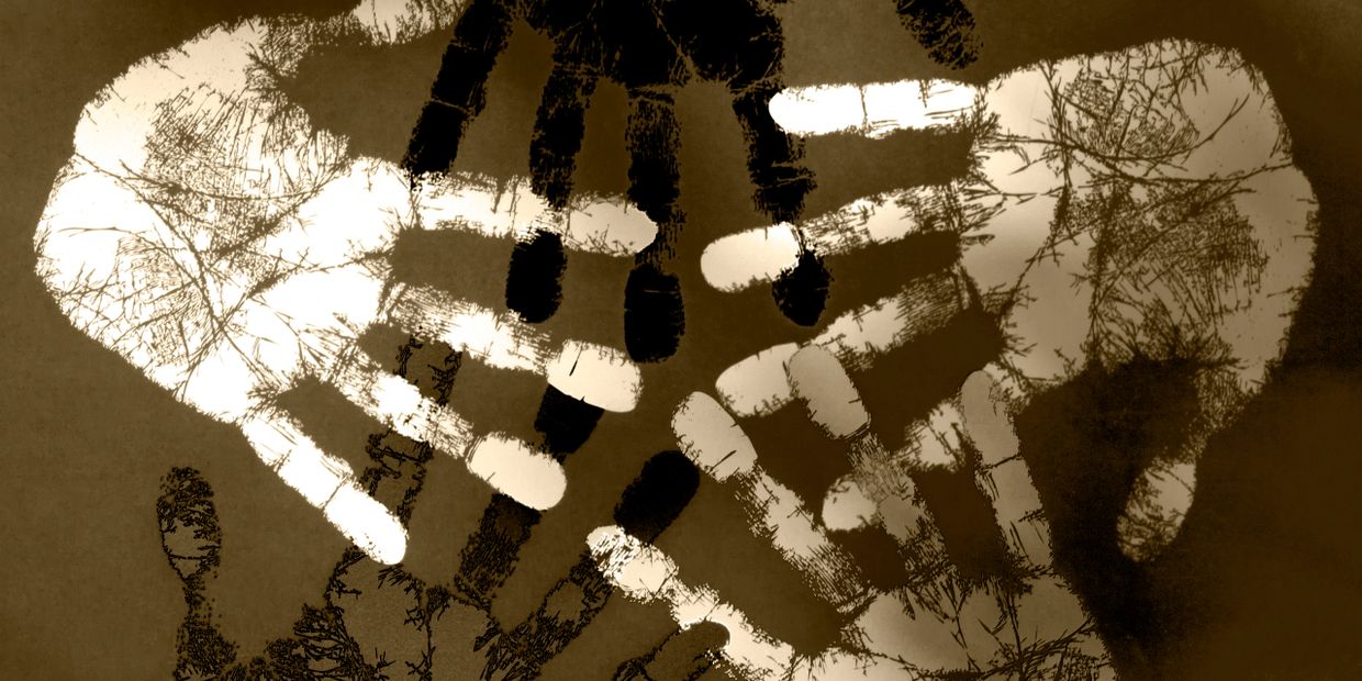 Artistic image of overlapping white and black handprints on a brown background.