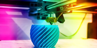 3D printer creating a blue spiral object with colorful lighting.