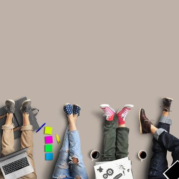 Four people sitting with legs extended, surrounded by laptops, coffee, and colorful notes.