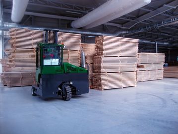 Forklift moving wooden planks in a warehouse.