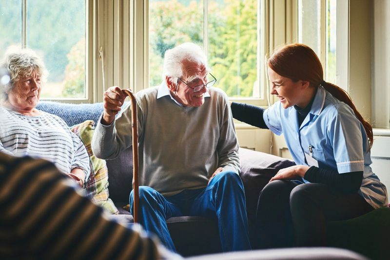 Smiling female nurse talking with elderly couple at home