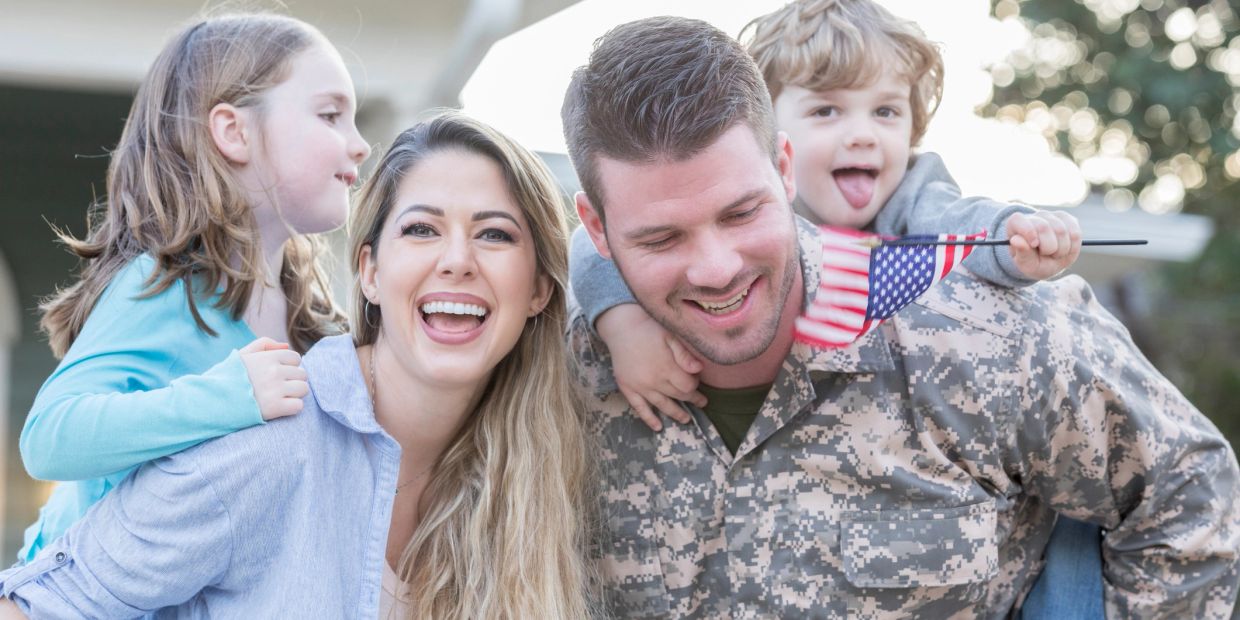 Happy family with a soldier and children with an American flag.