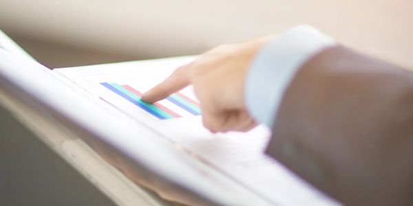 Person pointing at a colorful bar chart in a report.