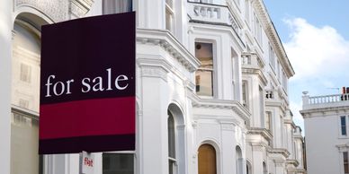 White Victorian-style flats with a 'for sale' sign outside.