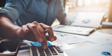 Person using a calculator with financial documents on the desk.
