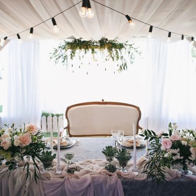 Elegant table setup with floral arrangements and candles under string lights.
