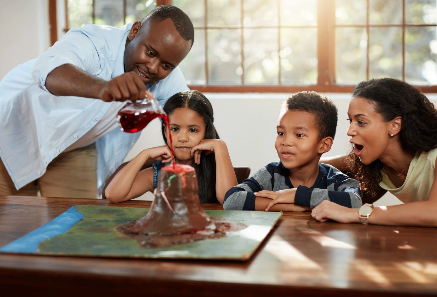 Family watching a homemade volcano erupt during a science experiment.