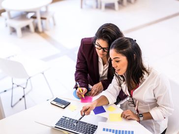 Two women collaborating on laptop