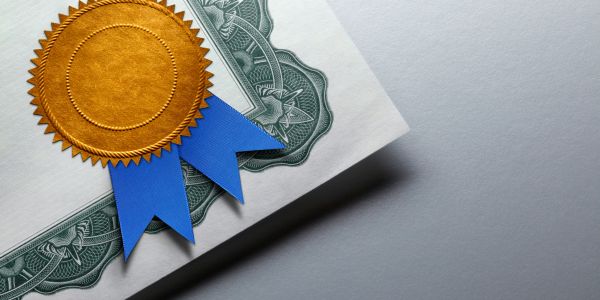 Close-up of a certificate with a gold seal and blue ribbon.