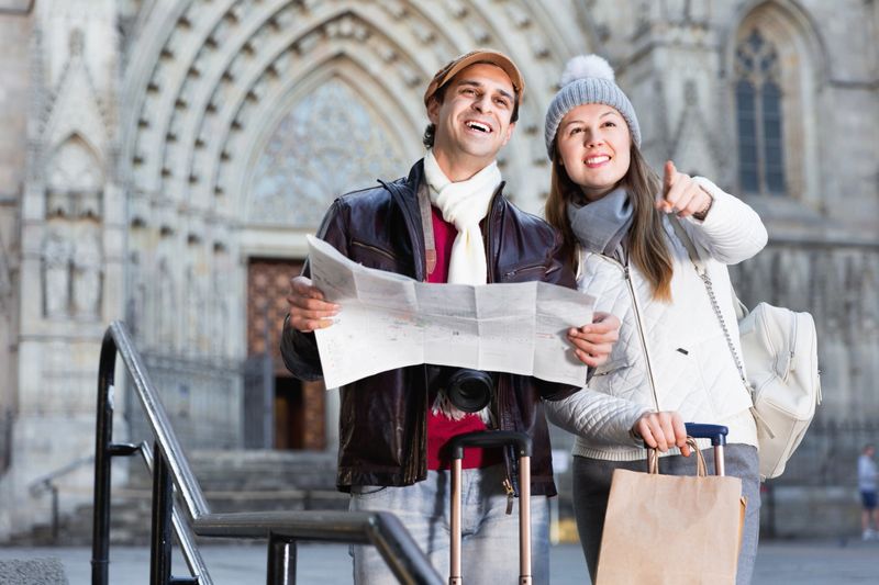 Happy cheerful positive smiling man and woman with map and package looking attraction outdoors
