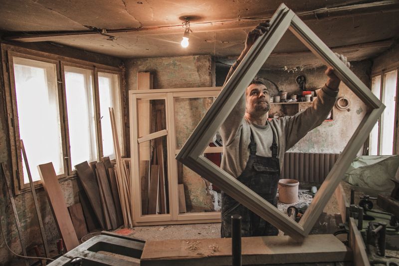 Mature carpenter making window frame in the workshop