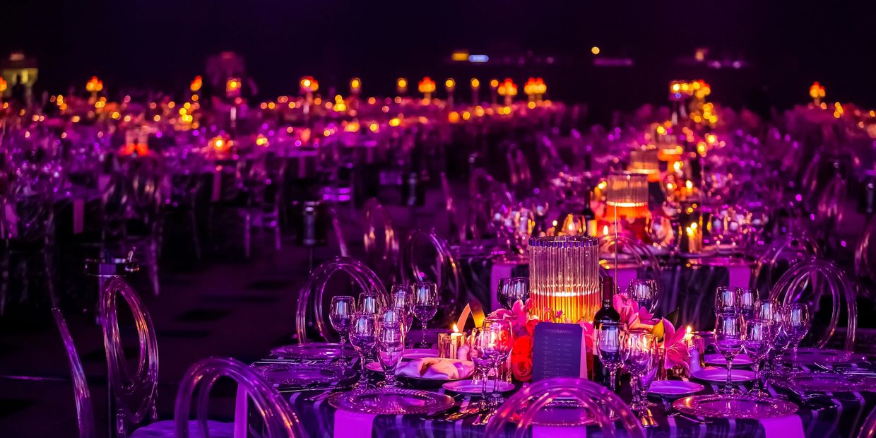 Elegant banquet tables lit with warm candlelight and purple ambiance.