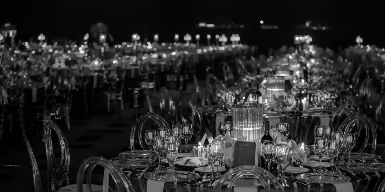 Elegant banquet tables set for a formal event with glowing centerpieces.