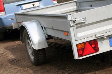 Metal utility trailer attached to a vehicle.