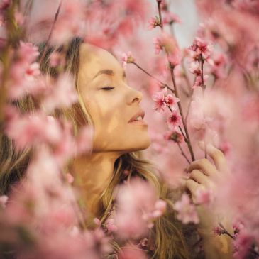 Woman enjoying the scent of pink blossoms.