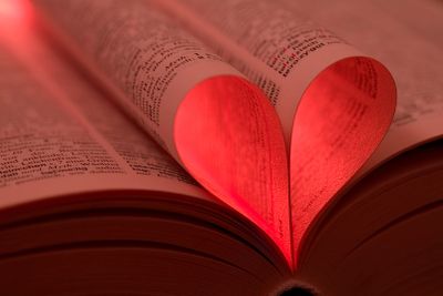 Pages of a book folded into a heart shape with red lighting.