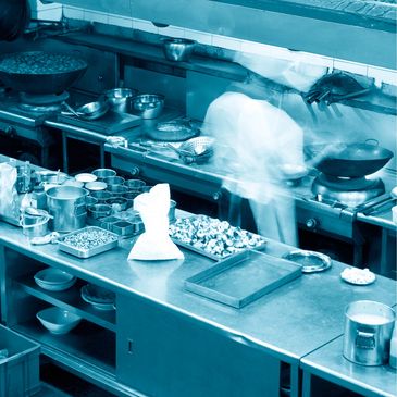 Busy kitchen with a chef preparing food and organized ingredients.