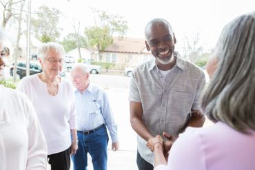 People greeting each other warmly outdoors in a friendly setting.
