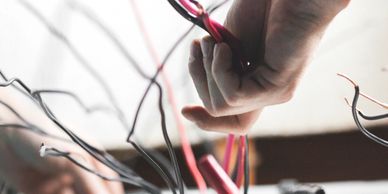 Close-up of hands working with electrical wires in a metal box.