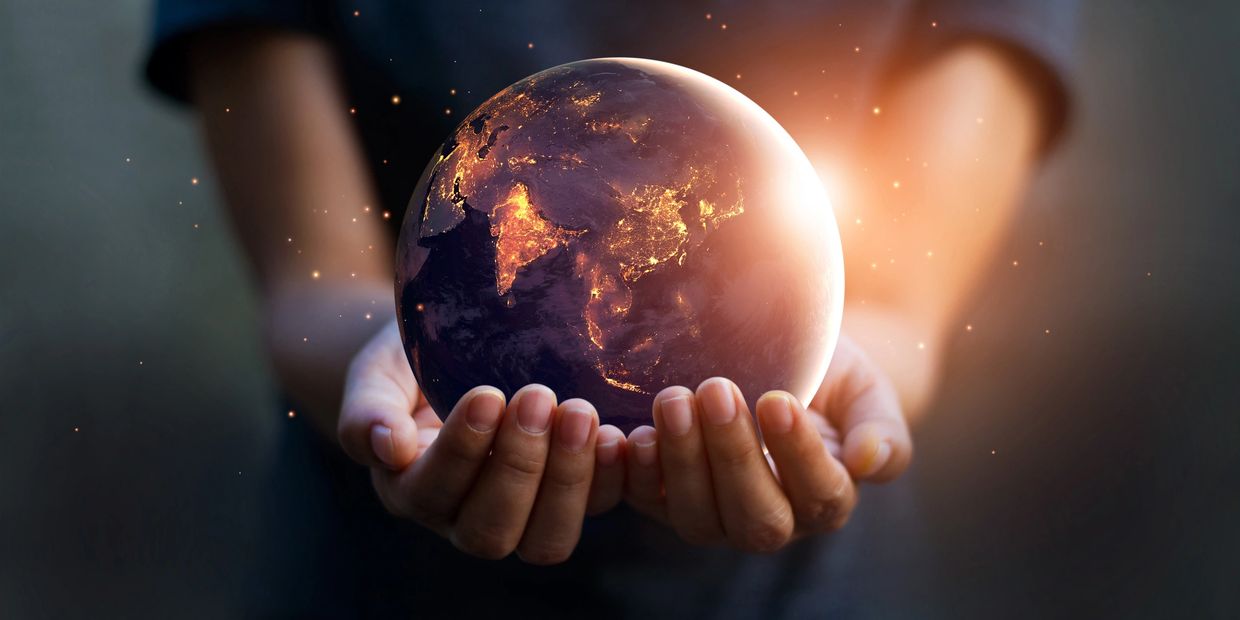 Hands holding a glowing Earth at night.