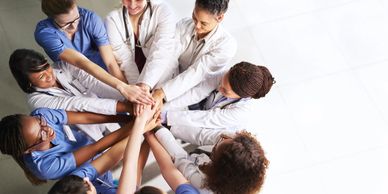 A group of diverse healthcare professionals joining hands in unity and teamwork.
