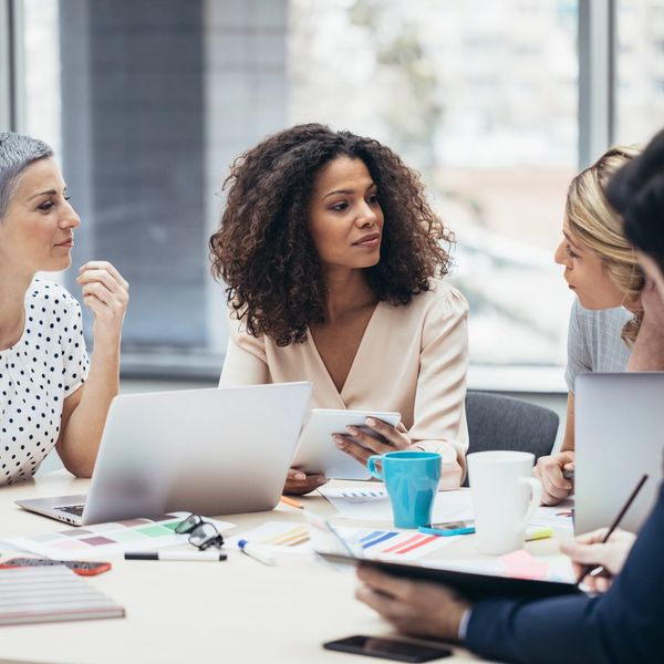 Four professionals engaged in a collaborative office meeting around a table.