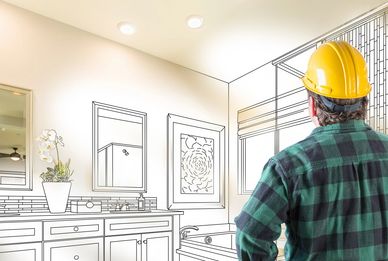 Contractor assessing bathroom renovation plans with tools on his belt.