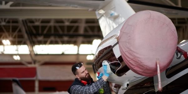 Man cleaning an aircraft engine indoors.